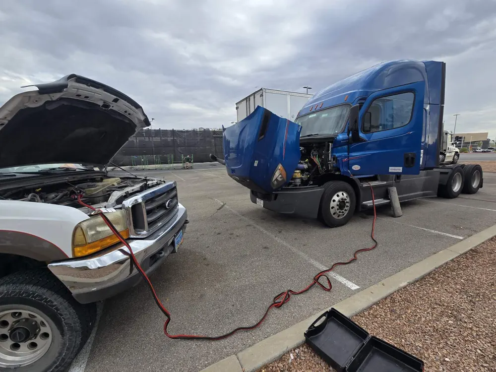 Tech Care service truck jump-starting a blue Freightliner semi