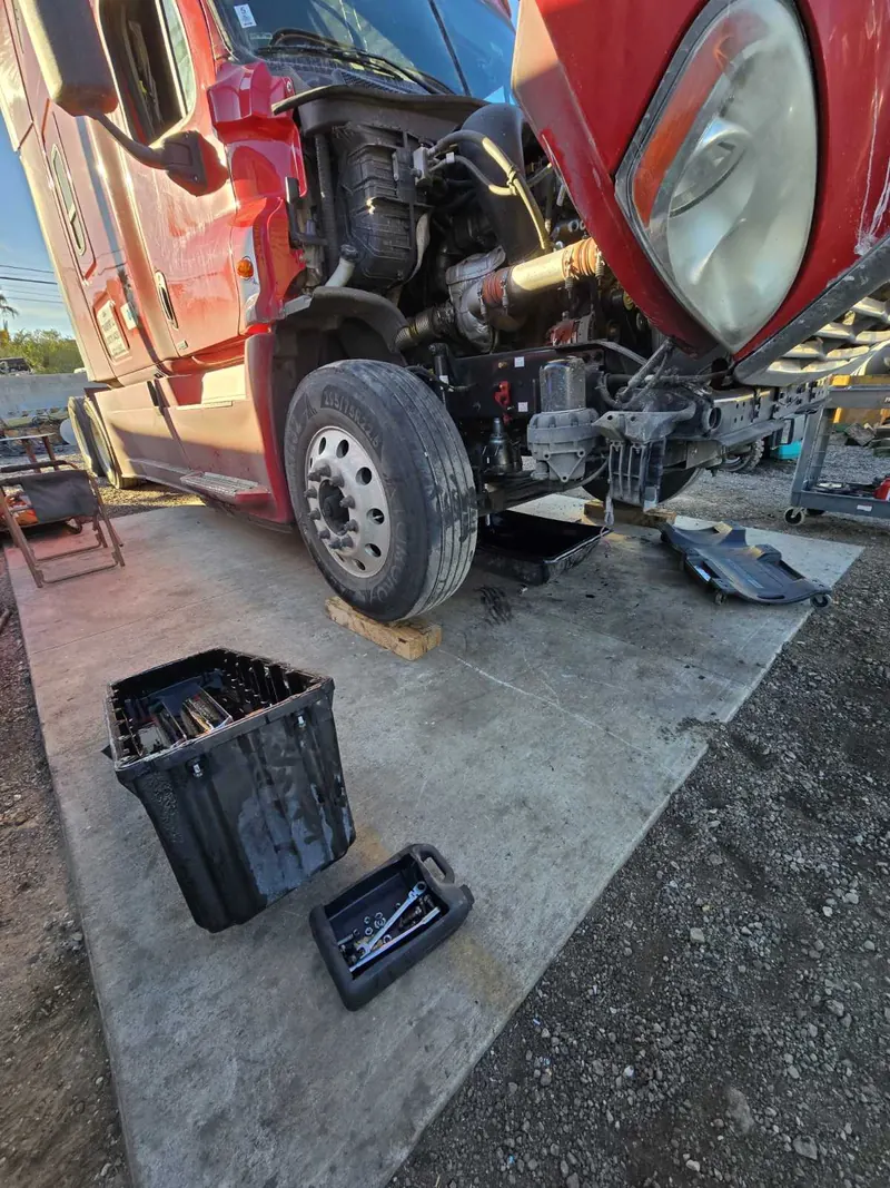 Mechanic repairing a red semi truck on-site